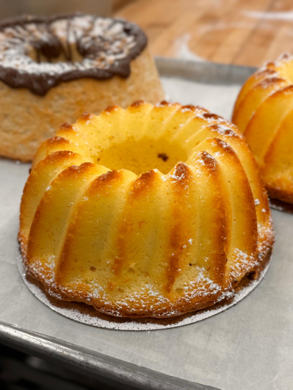 Golden bundt cakes on a baking tray dusted with powdered sugar