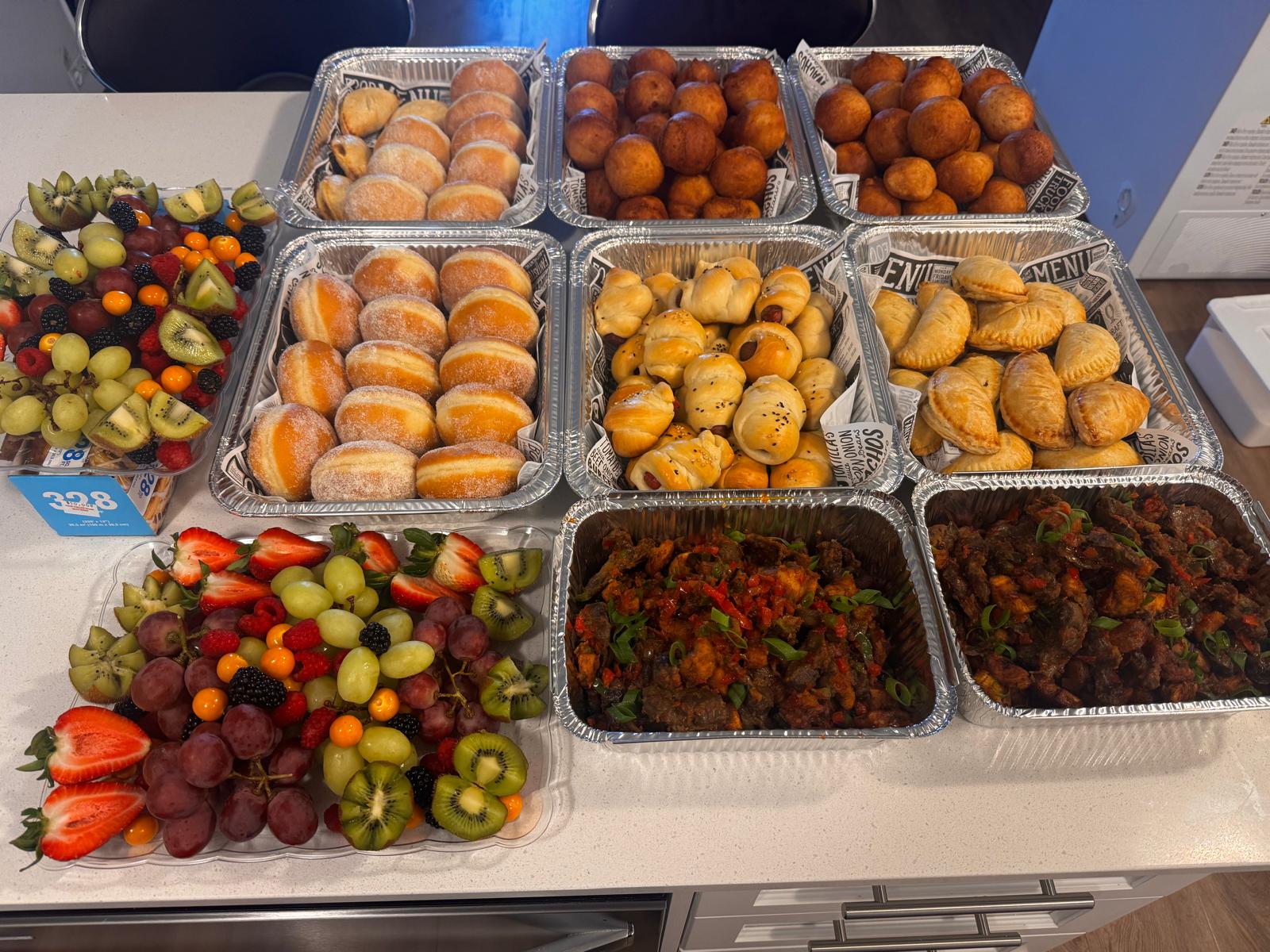 Full catering event spread with pastries, suya, puff puff and fruit
