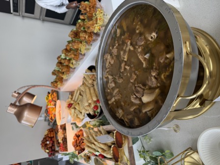 Gold chafing dish with pepper soup, buffet spread behind
