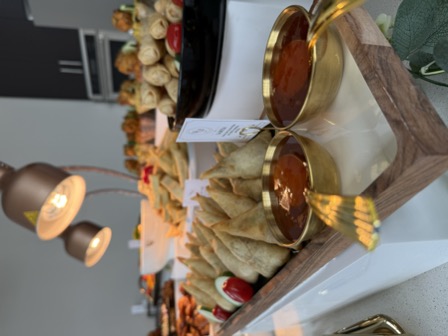 Samosas in a wooden tray with gold dipping sauce bowls