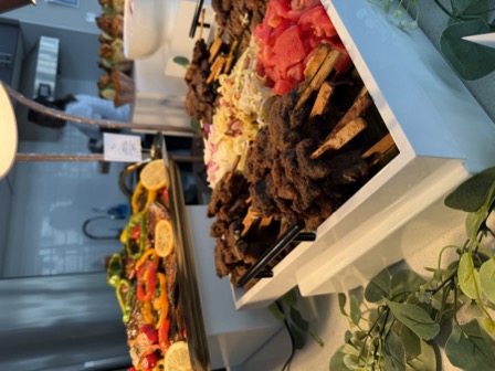 Suya skewers with grilled fish behind at a catering event