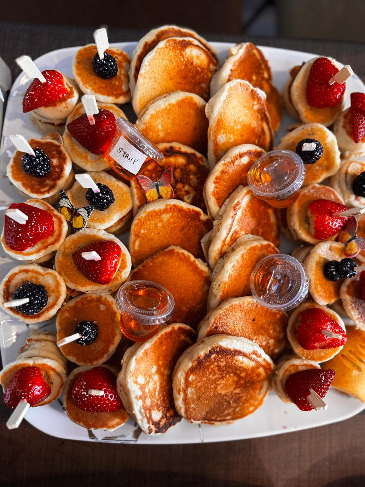 Mini pancakes on sticks with syrup and berries