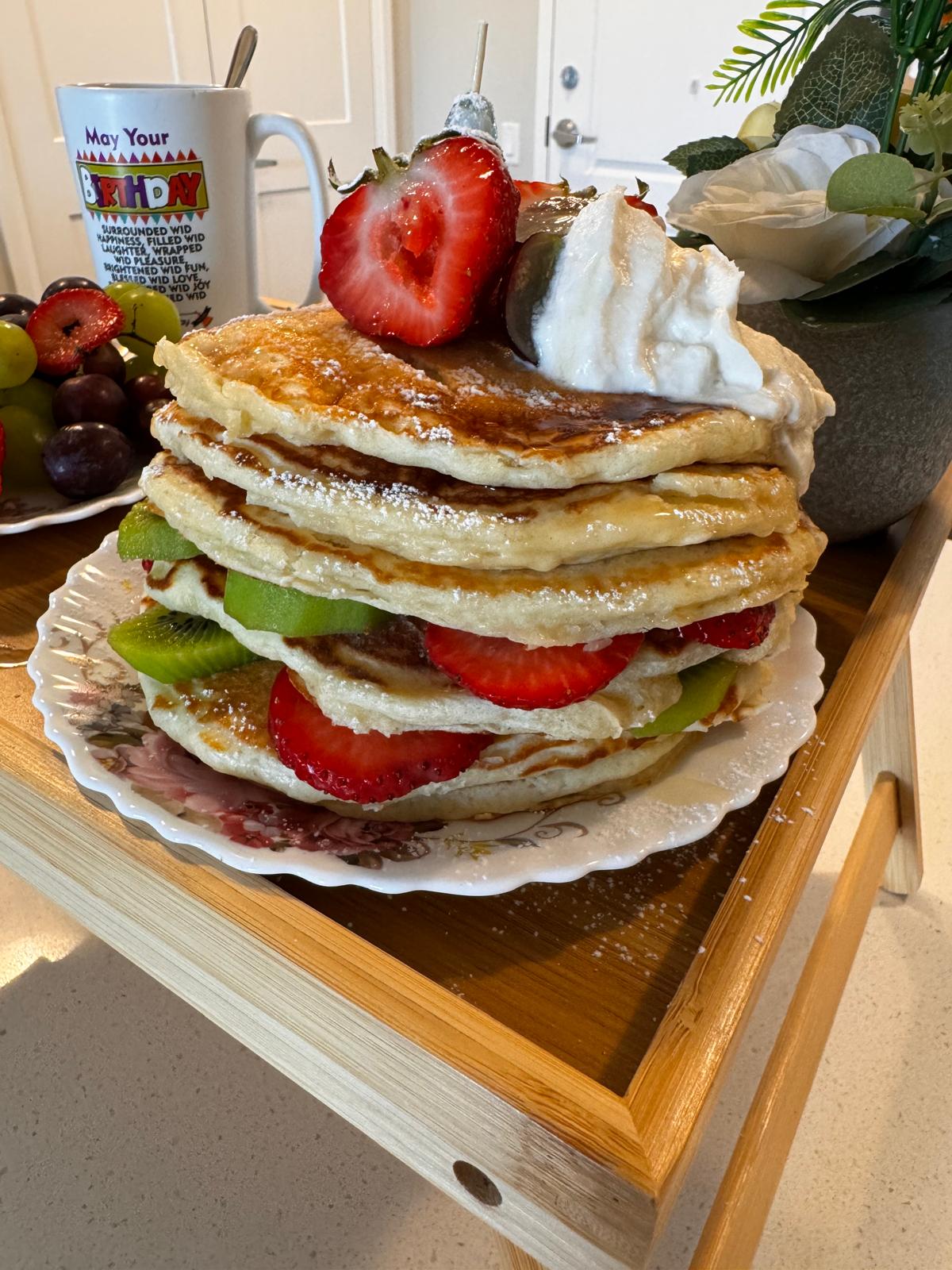 Tall stacked pancake tower layered with kiwi and strawberries
