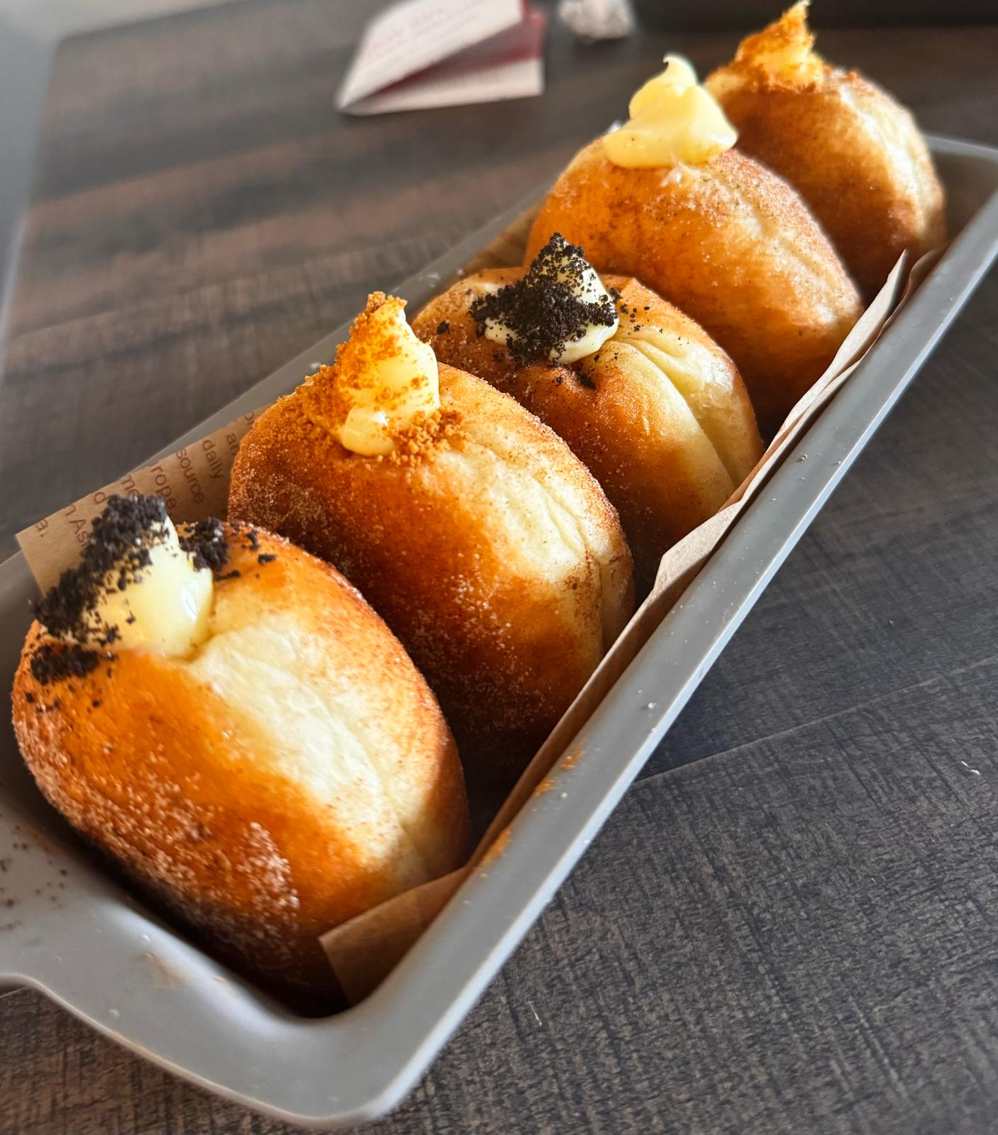 Row of filled stuffed buns with cream topping in a tray